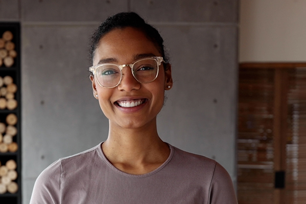 Young woman wearing glasses smiling at the camera.